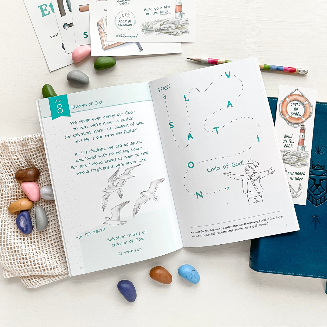 Educational materials including a coloring book and cards on a white surface with colorful stones.