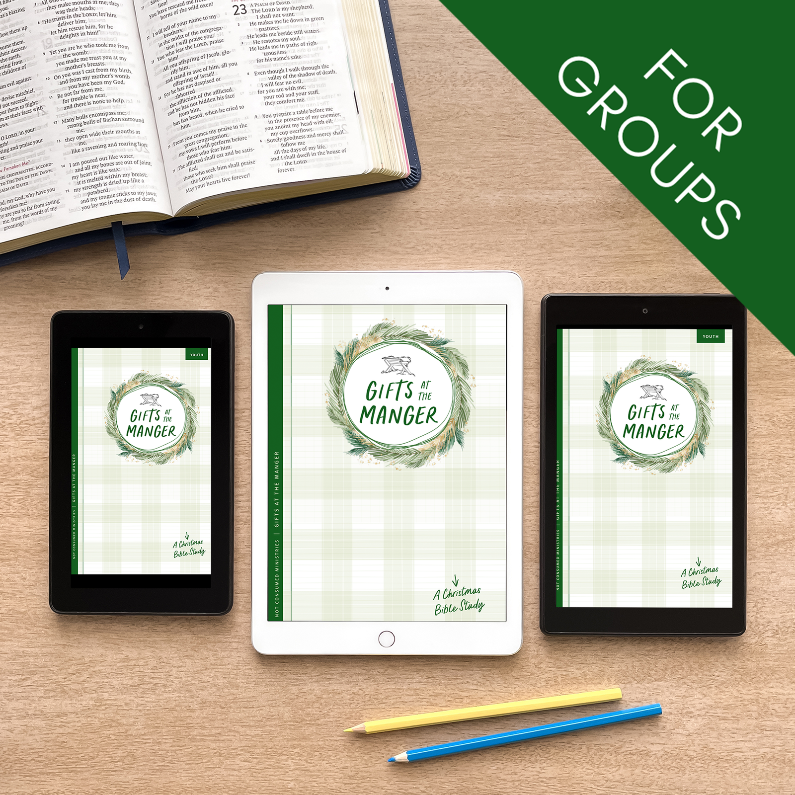 Tablet and smartphones displaying a digital version of 'Gifts of the Manger' on a wooden surface with an open book.