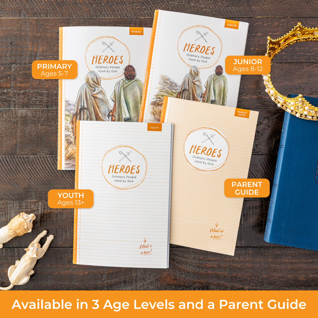 Book titled 'HEROES: Ordinary People Used by God' on a wooden surface with other related materials.